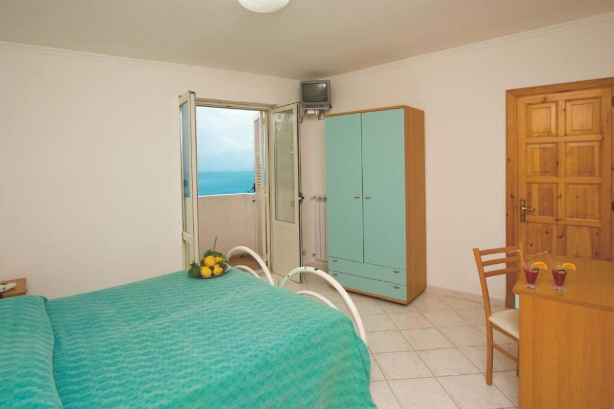 Une chambre à coucher avec un lit, une petite table avec des boissons, une télévision et une armoire.