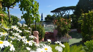 Ein Garten mit weißen Gänseblümchen, einer Pergola und Blick aufs Meer.