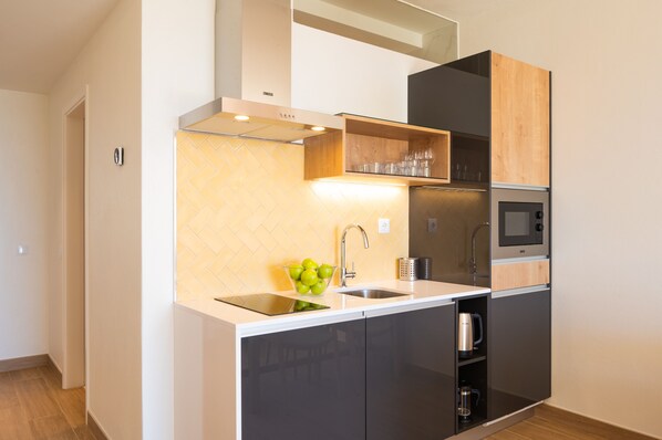 A modern kitchen with a built-in microwave, sink, and a wooden cabinet above the countertop. - Vila Luz (Lagos)