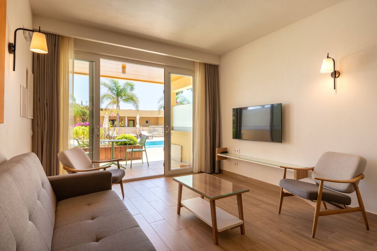 A modern living room with a sofa, armchairs, a coffee table, and a TV.