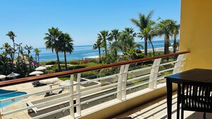 A balcony with a pool, lounge chairs, and a view of the ocean. - Vila Luz (Lagos)
