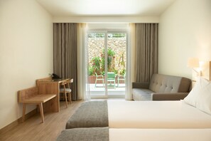 Habitación de hotel con cama, escritorio, silla, sofá y vista al exterior.