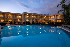 Un hotel con piscina, varios balcones y zonas de estar al aire libre.