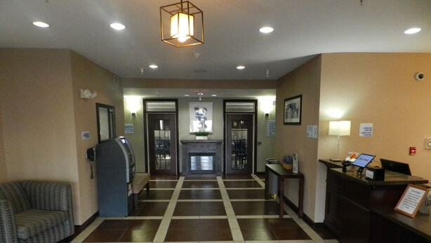 A hotel lobby with a check-in counter, a reception desk, a seating area, and a check-out counter. - Pike Inn Le Roy - Bloomington Southeast Area (Le Roy)