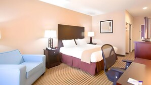 A hotel room with a bed, a desk, a chair, a sofa, and a nightstand with lamps. - Pike Inn Le Roy - Bloomington Southeast Area (Le Roy)