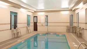 A swimming pool with a tiled deck, a changing room, and a seating area with chairs. - Pike Inn Le Roy - Bloomington Southeast Area (Le Roy)