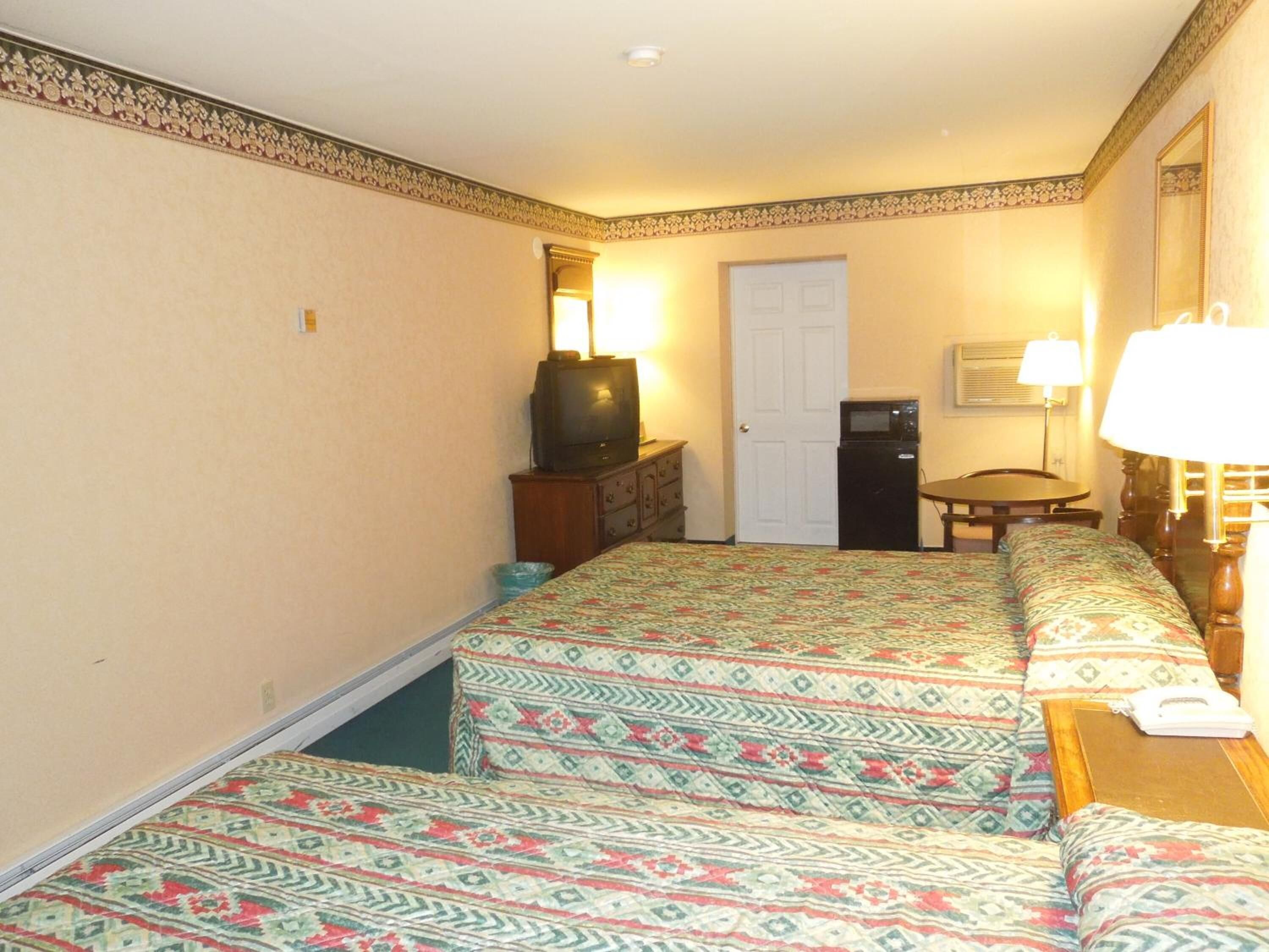 A hotel room with a bed, a television, a desk, and a microwave.