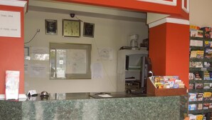A reception desk with a clock, a coffee machine, and a bulletin board with various notices. - Value Inn (East Stroudsburg)