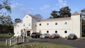 A two-story motel with a parking lot and a small bridge leading to the entrance. - Value Inn (East Stroudsburg)
