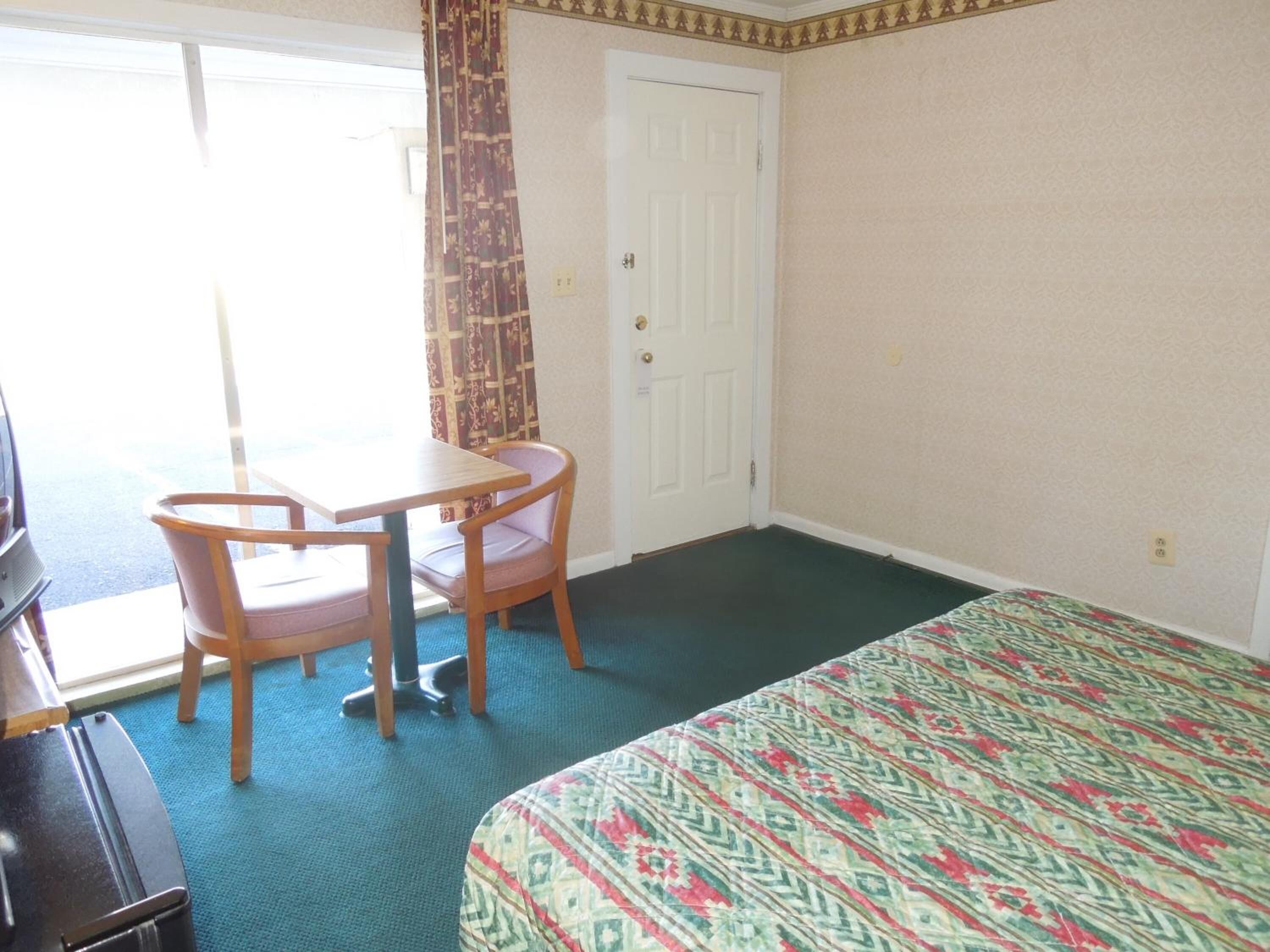 Una habitación de hotel con una cama, un escritorio, una silla y un televisor.