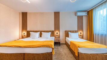 Habitación de hotel con dos camas, cabecero de madera, aire acondicionado de pared y ventana con cortinas.