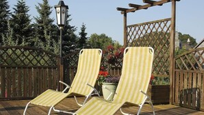 Two striped lounge chairs on a wooden deck with a wooden pergola and a metal gate in the background. - Landgasthof Haus zur Sonne (Hallenberg)