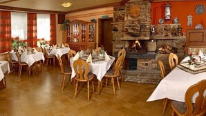 A dining area with multiple tables and chairs, a fireplace, and traditional decor. - Landgasthof Haus zur Sonne (Hallenberg)