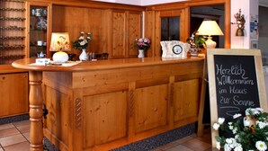 A wooden reception desk with a chalkboard sign, a clock, and various decorative items. - Landgasthof Haus zur Sonne (Hallenberg)