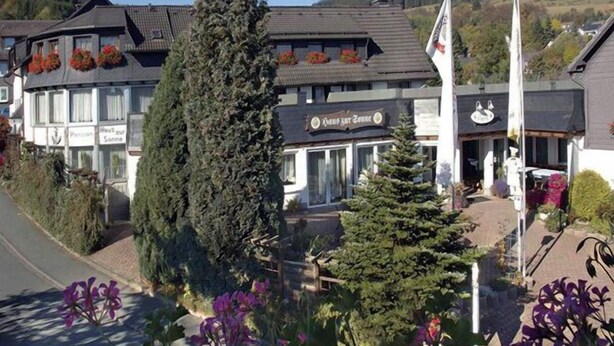 A building with a sign reading "Hotel zur Sonne" and a flagpole with a flag. - Landgasthof Haus zur Sonne (Hallenberg)