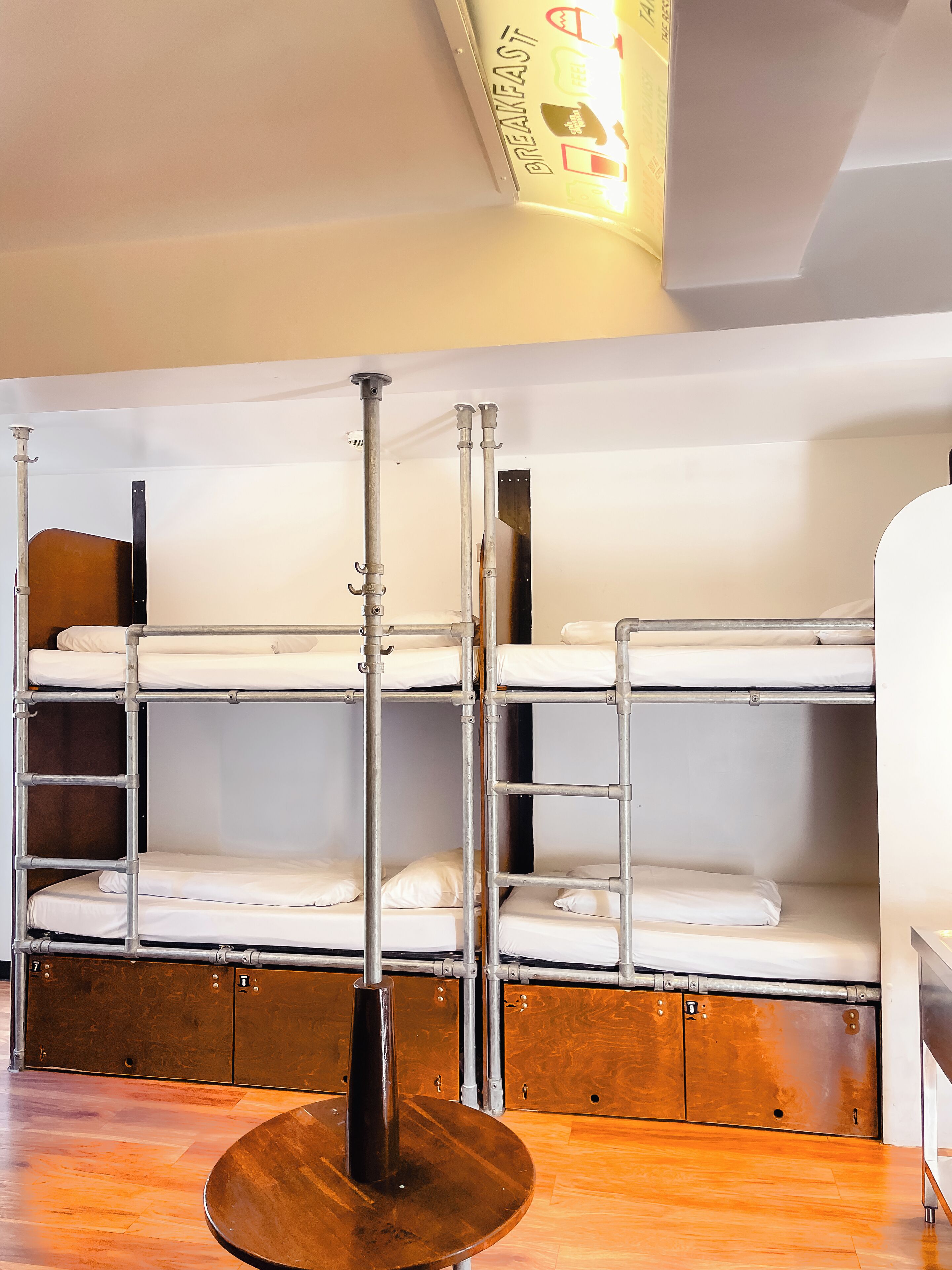 A bunk bed room with a metal pole in the center, wooden cabinets below, and a ceiling sign.