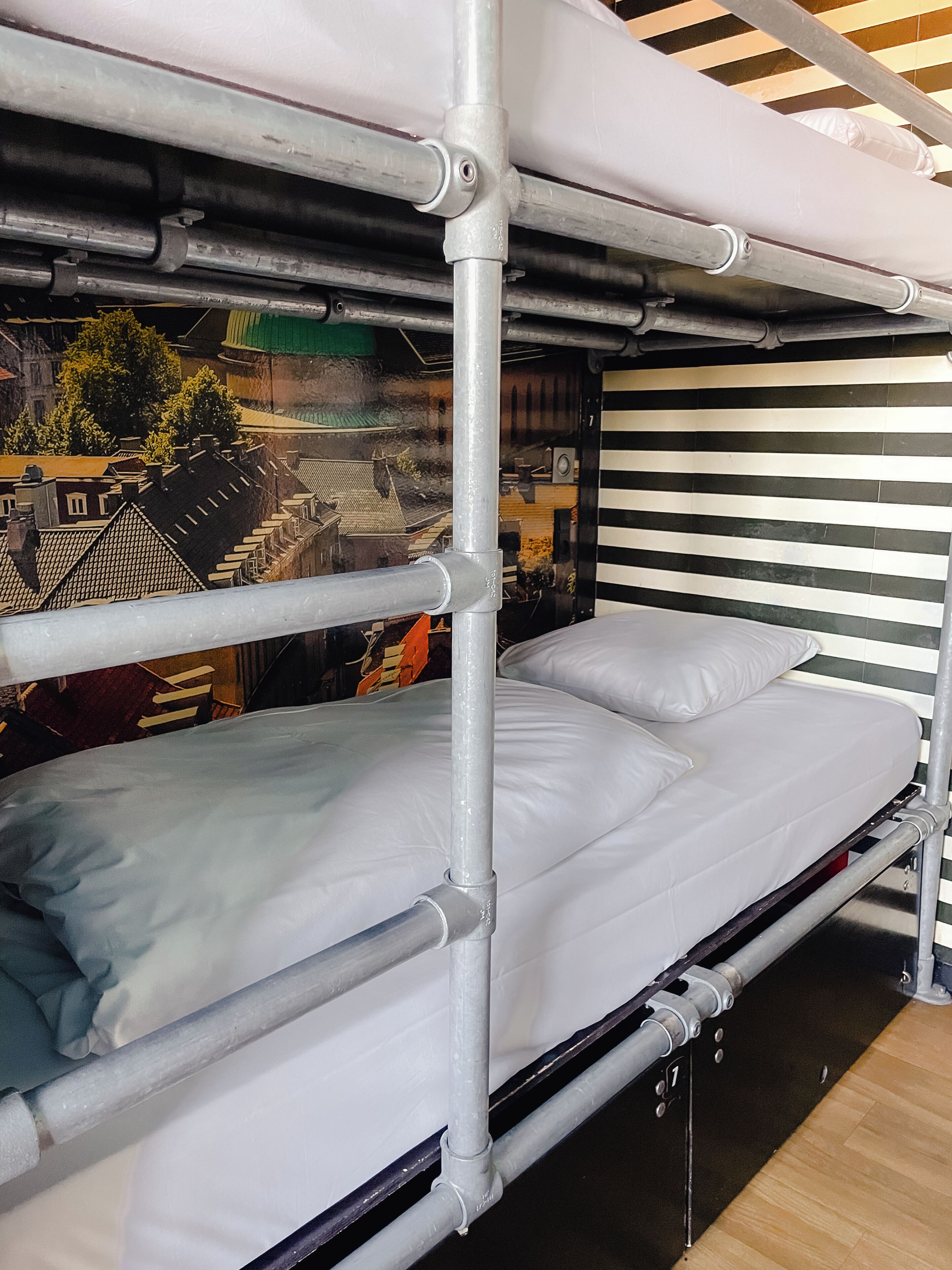 A bunk bed with metal railings, a white mattress, and a striped wall.