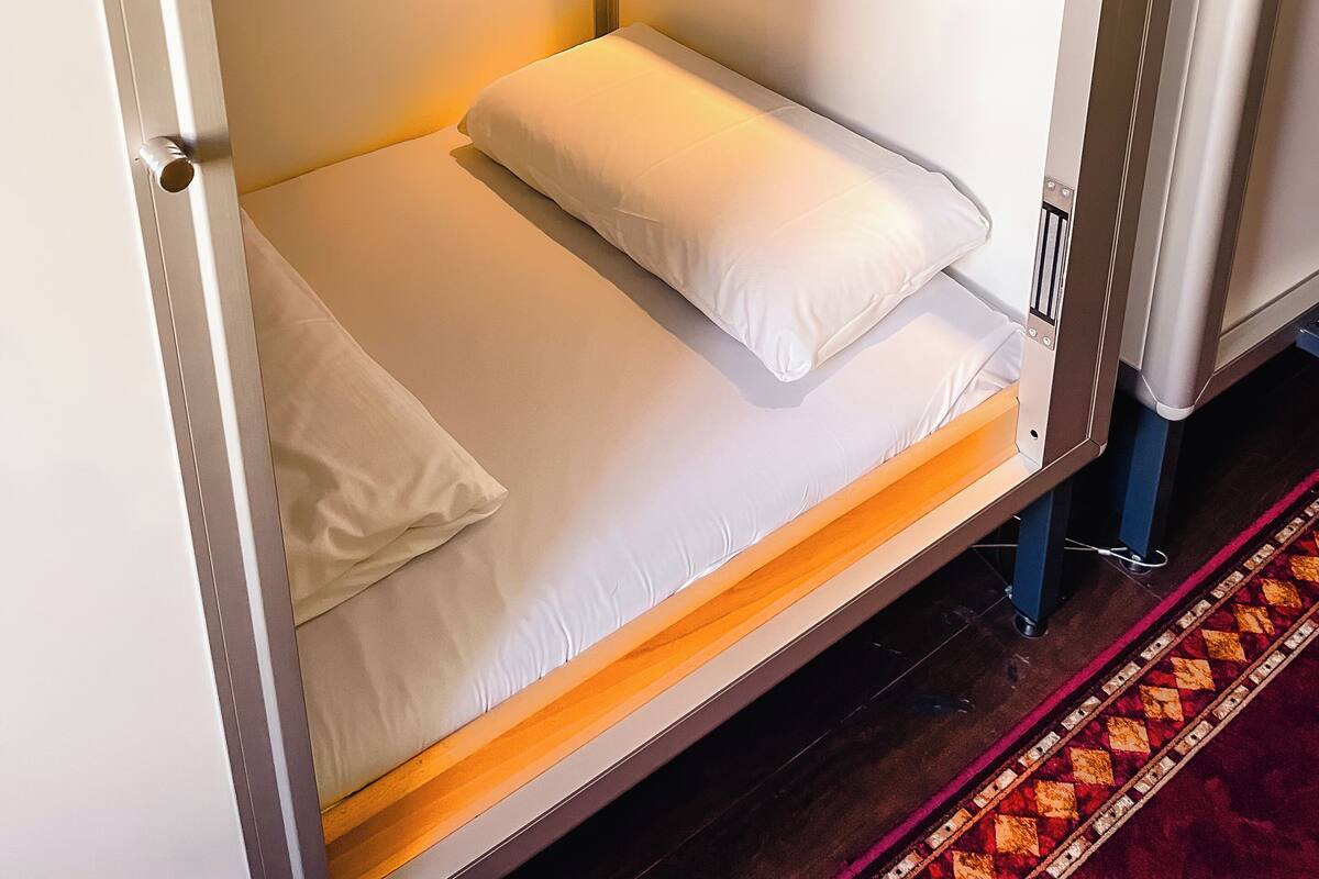 Un lit superposé avec une structure en bois et une tête de lit en métal.
