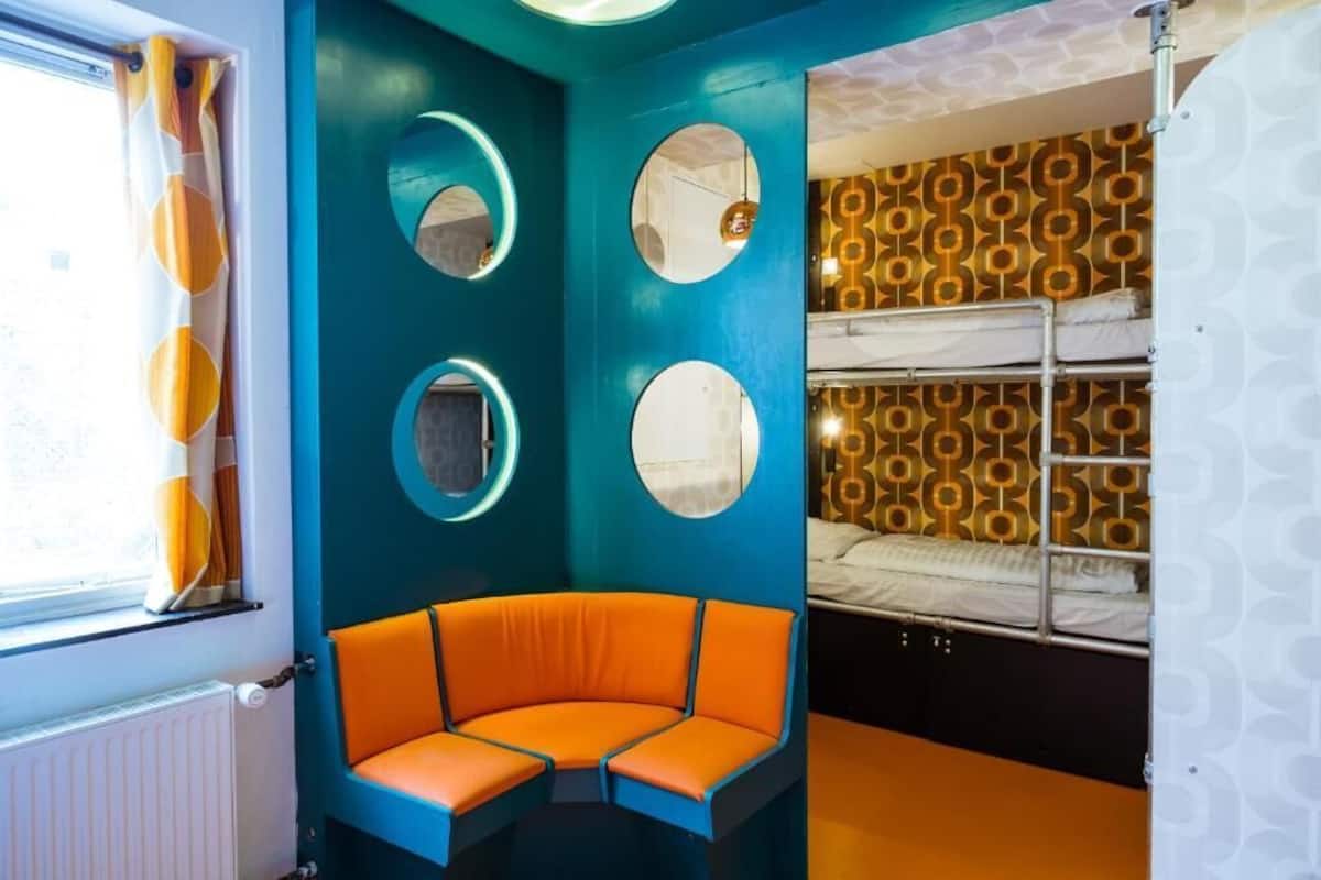 Une pièce avec un lit superposé, un espace salon circulaire et une fenêtre avec des rideaux.