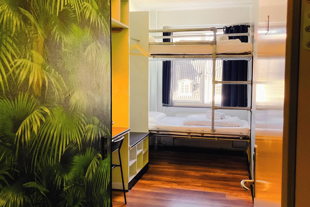 Une petite pièce comprenant un lit superposé, un bureau et une chaise.