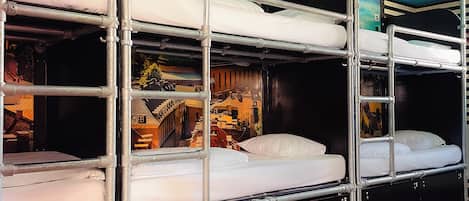 A bunk bed room with a mural on the wall, wooden flooring, and a ceiling light fixture.