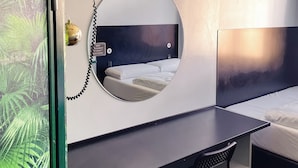 Una habitación de hotel moderna con una cama, un escritorio y un espejo redondo.