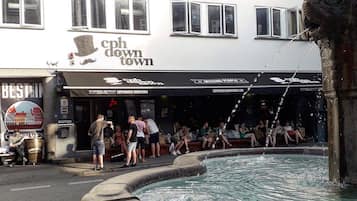 Ein öffentlicher Platz mit einem Brunnen, einem Gebäude mit der Beschriftung 'cph down town' und einem Schild mit 'BEST IN'.