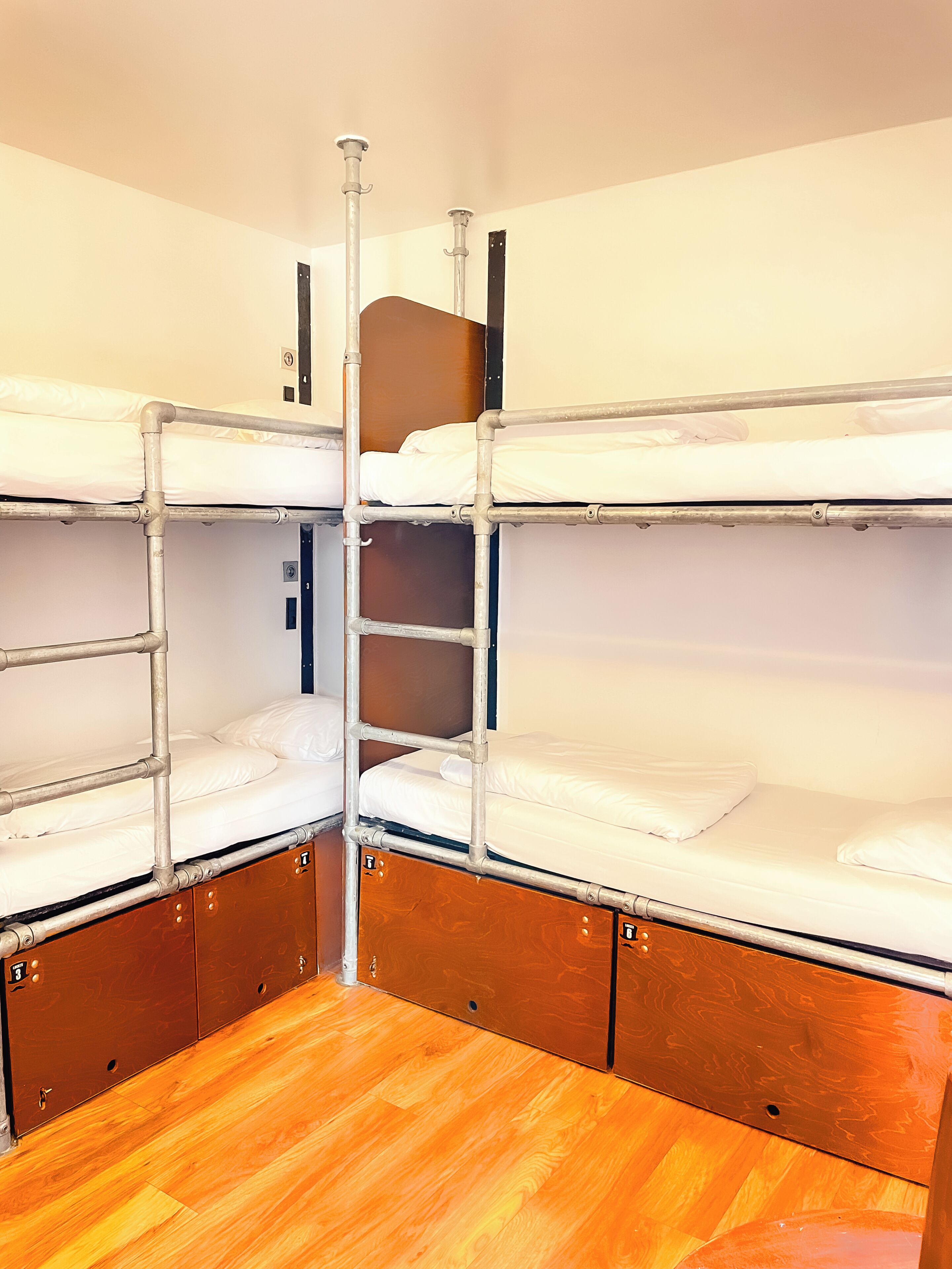 A bunk bed room with metal railings and wooden flooring.