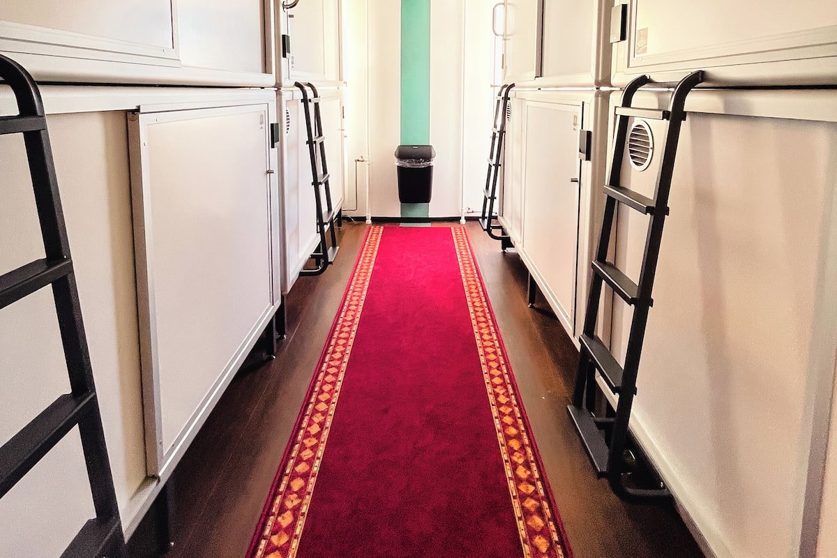 Un couloir avec un tapis rouge, des murs blancs et un plafond vert.