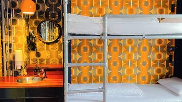 Ein Stockbett mit Metallgestell, ein Waschbecken, ein Spiegel und eine Wand mit Muster.