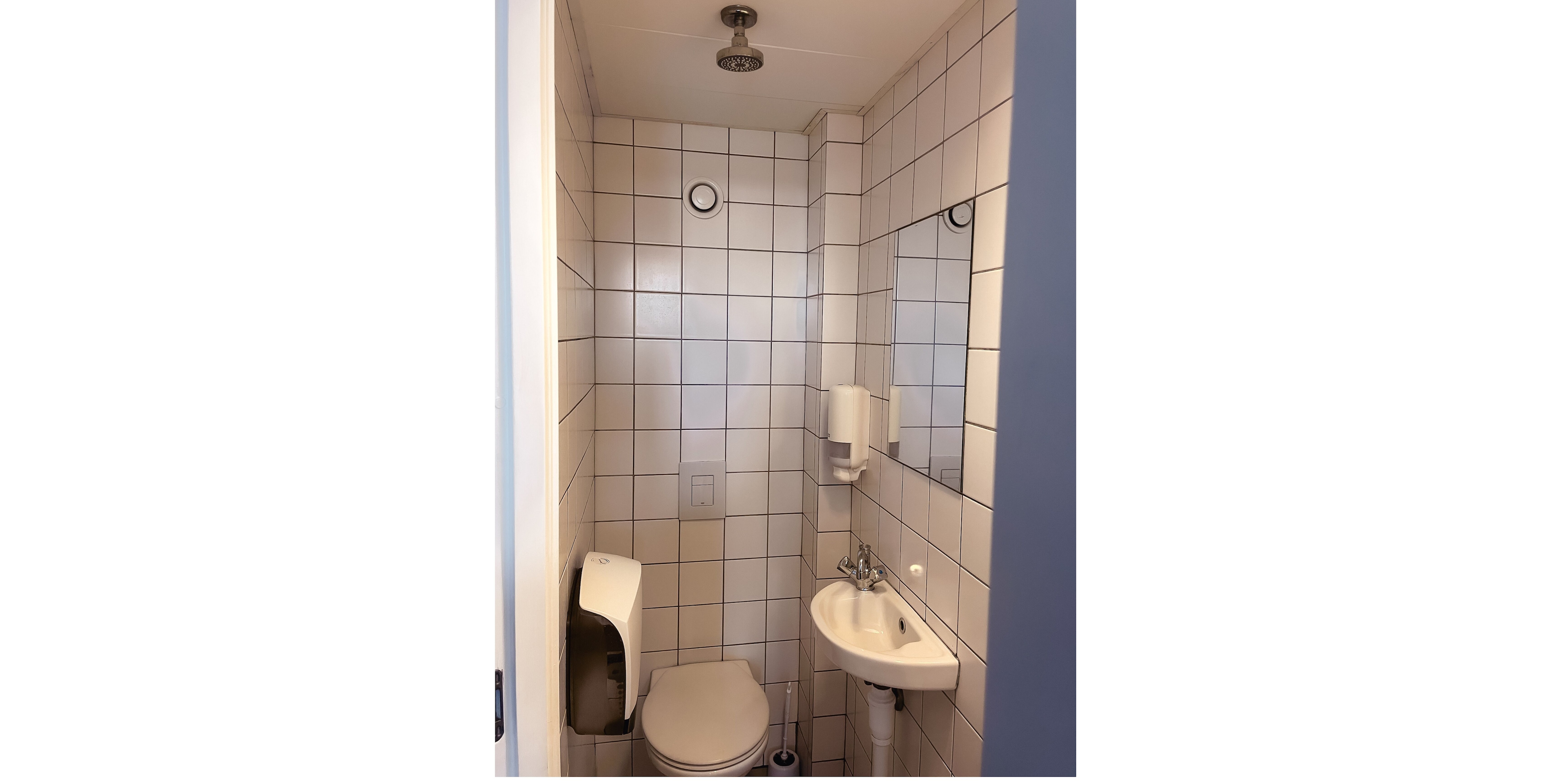 A small bathroom with a toilet, sink, and shower.