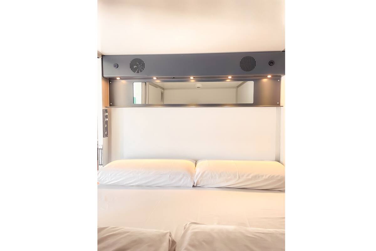 Un lit superposé avec une tête de lit qui comprend un miroir et des lampes.