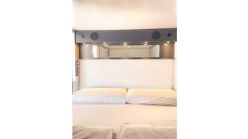 Una cama literera con cabecera que incluye un espejo y luces.