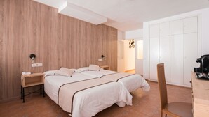 Une chambre avec deux lits, un mur en bois, une armoire blanche et un bureau avec une chaise.
