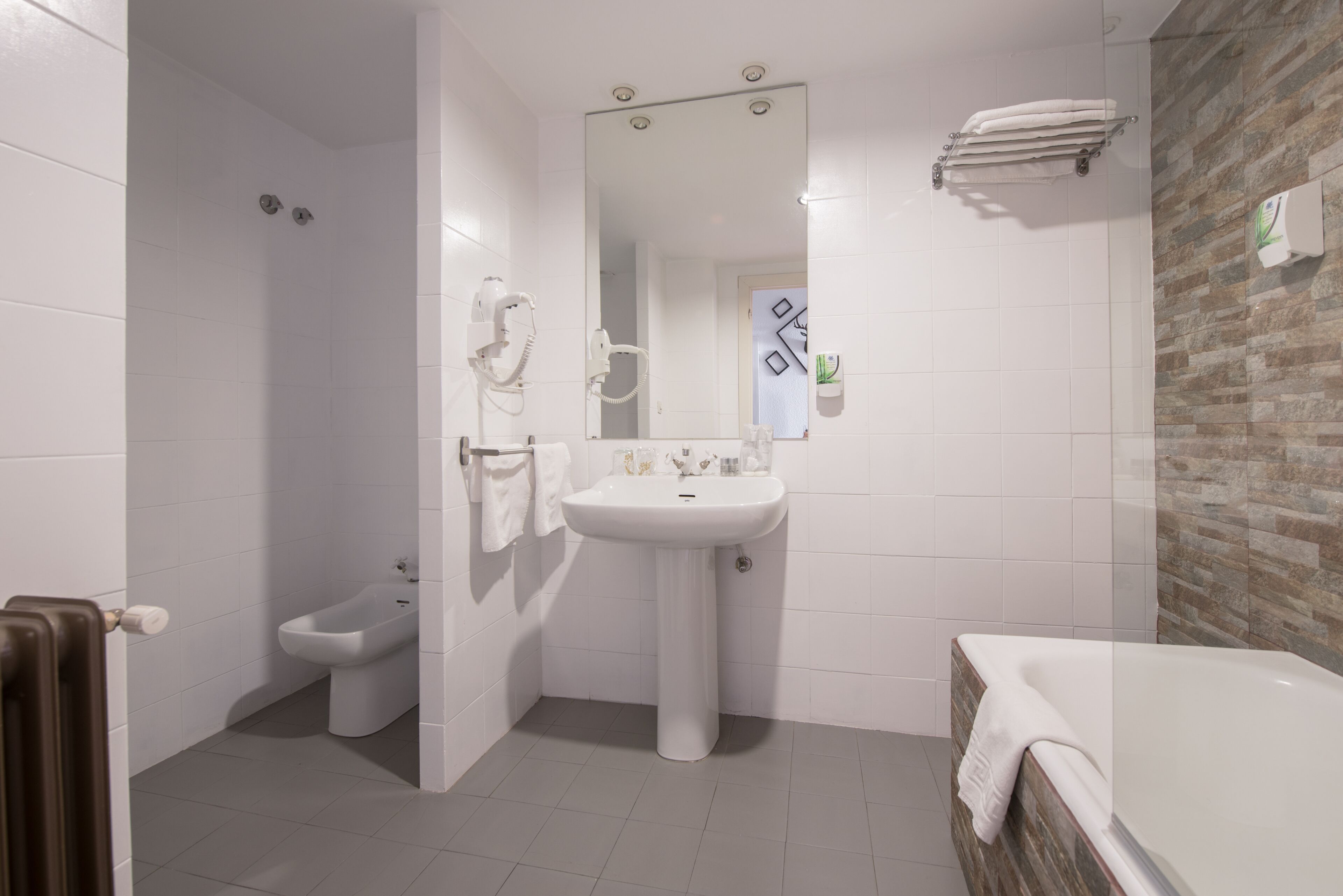 A modern bathroom with a bidet, a sink, and a bathtub.