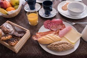 A breakfast table with various food items including pastries, bread, cheese, and sliced meats.