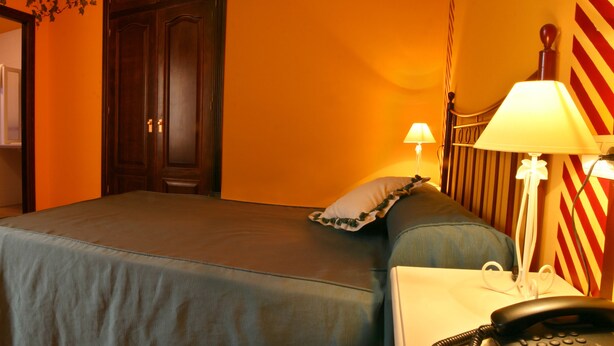 Une chambre d’hôtel équipée d’un lit, d’une table de chevet, d’une lampe et d’un téléphone.