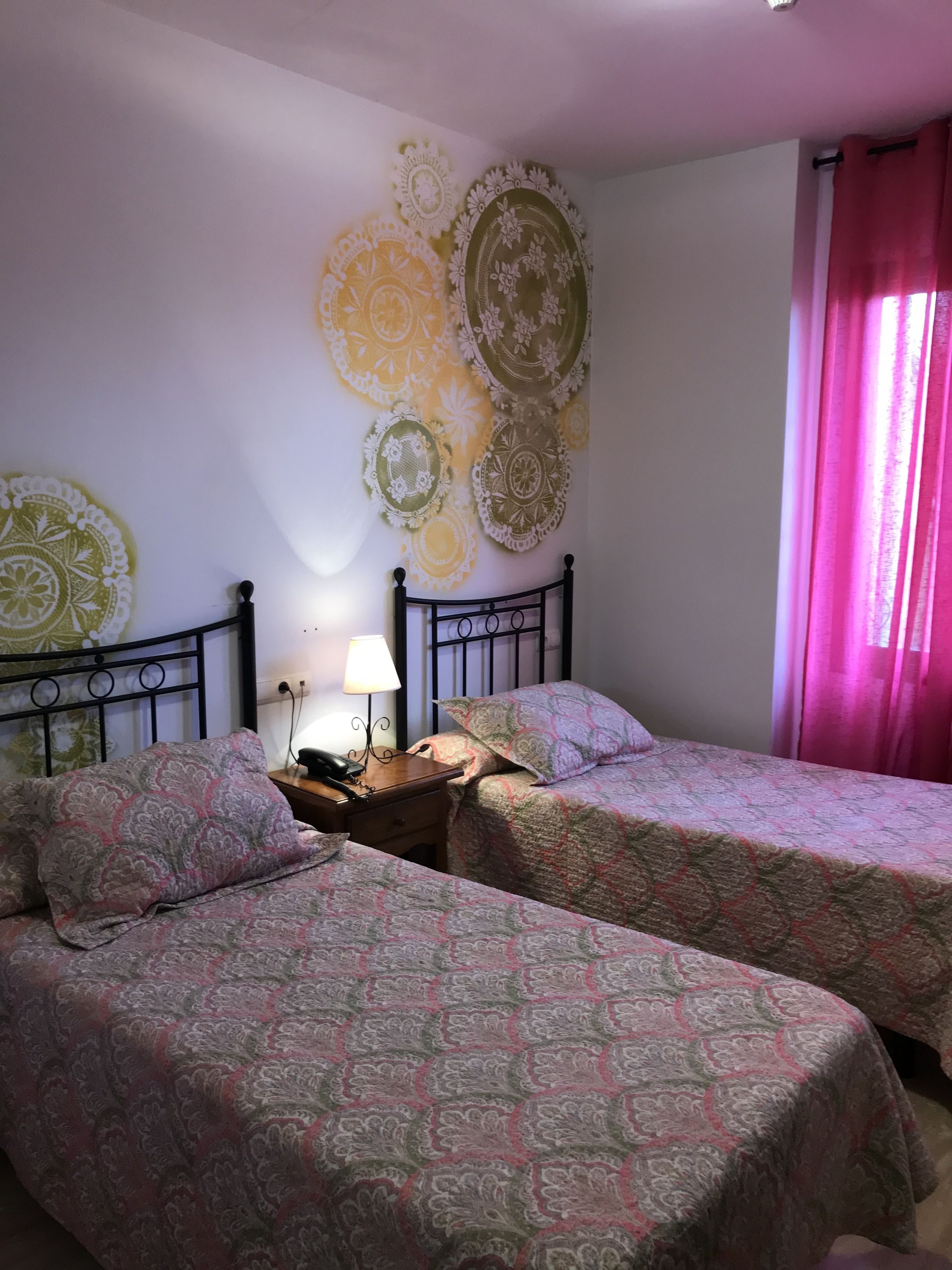 A room with two beds, a nightstand with a lamp, and decorative wall art.