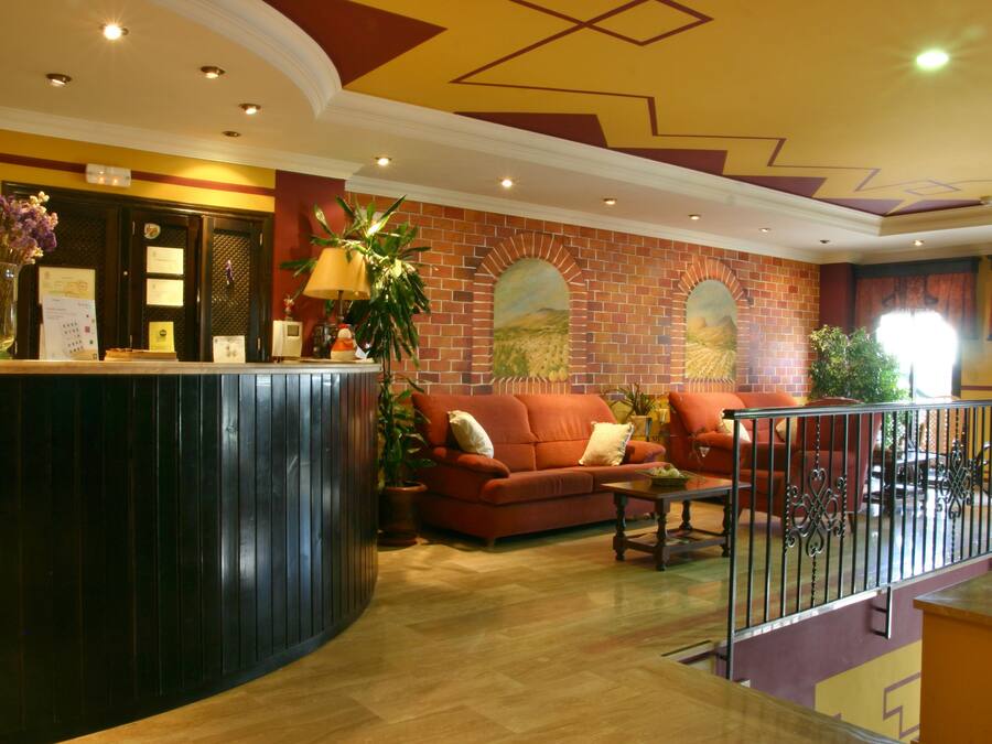 A reception area with a reception desk, a red sofa, a coffee table, and a brick wall with a mural.