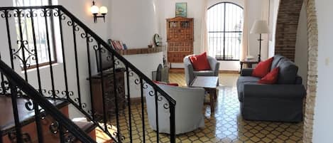 Un salón espacioso con escaleras, chimenea y un gran ventanal.