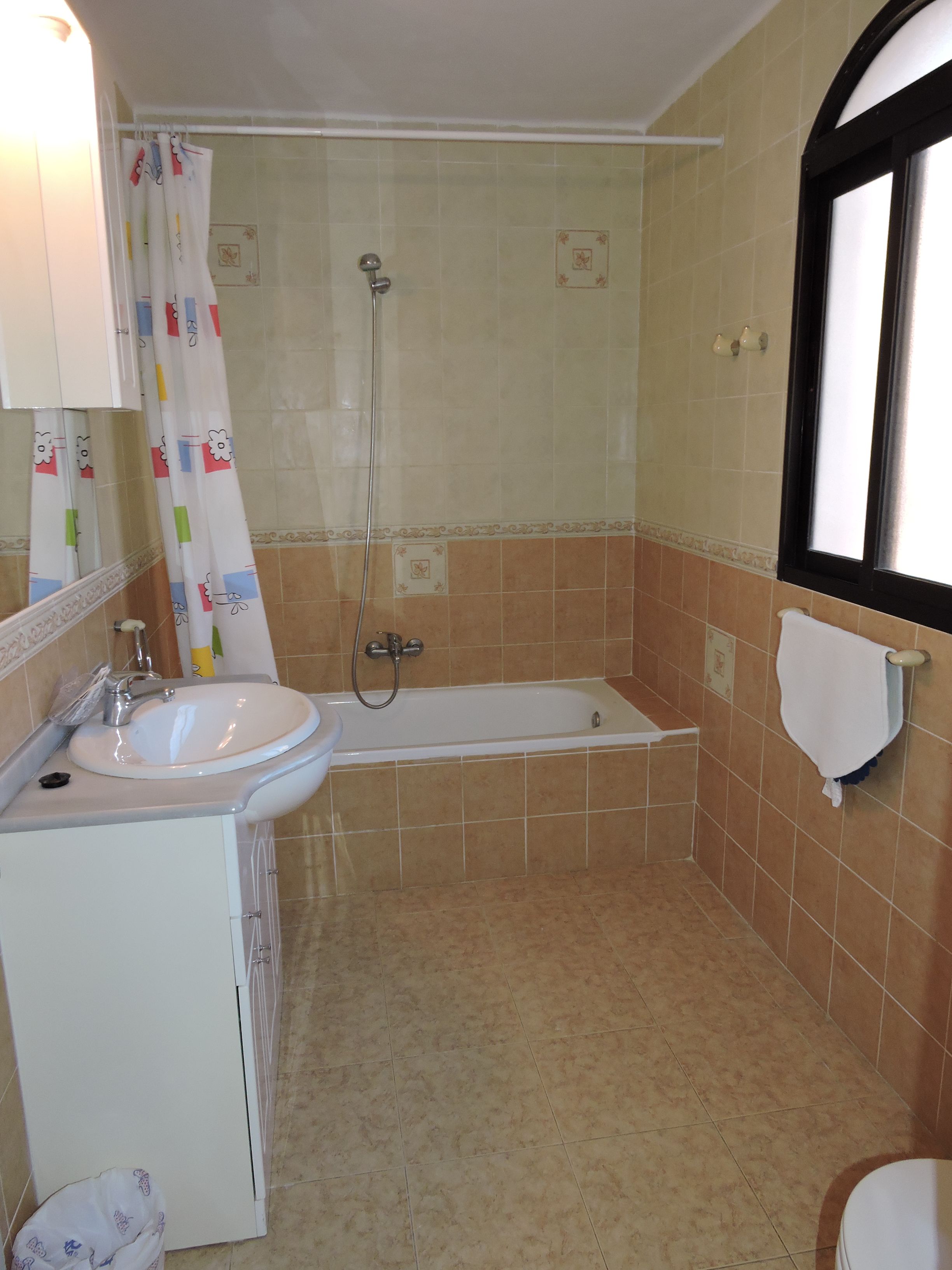 A bathroom with a sink, bathtub, shower, and a window.