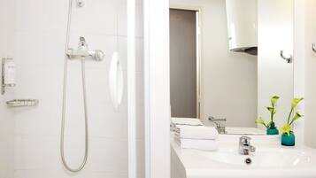 Un baño moderno con ducha, lavamanos y espejo.
