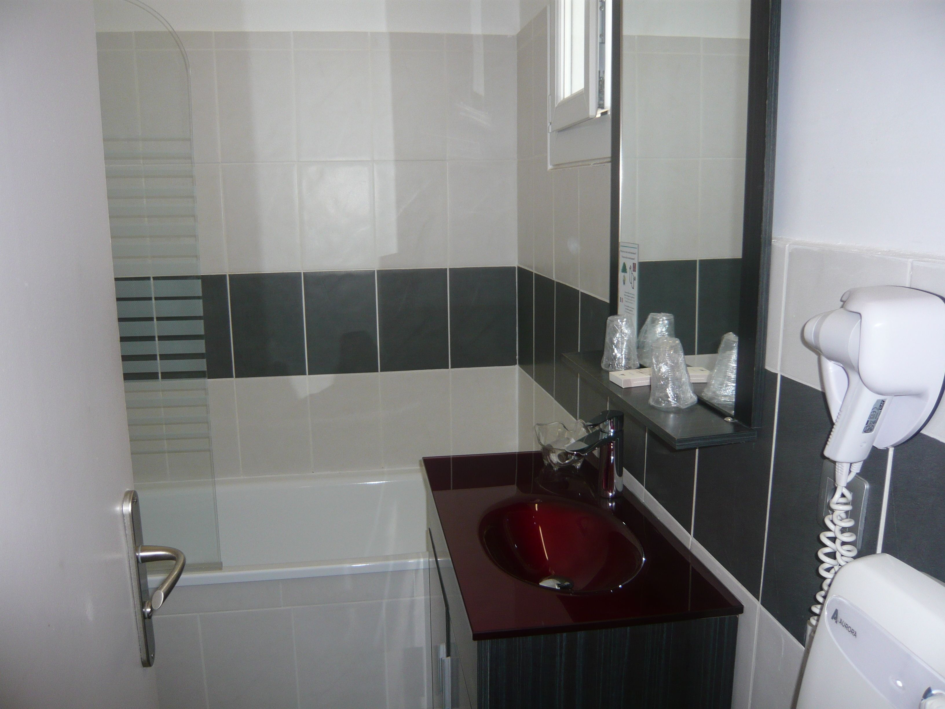 Un baño con un lavabo rojo, un secador blanco y un espejo.