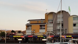 A waterfront hotel with balconies, a restaurant, and a port area.