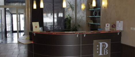 A reception desk with a dark finish, a glass partition, and a logo on the wall.