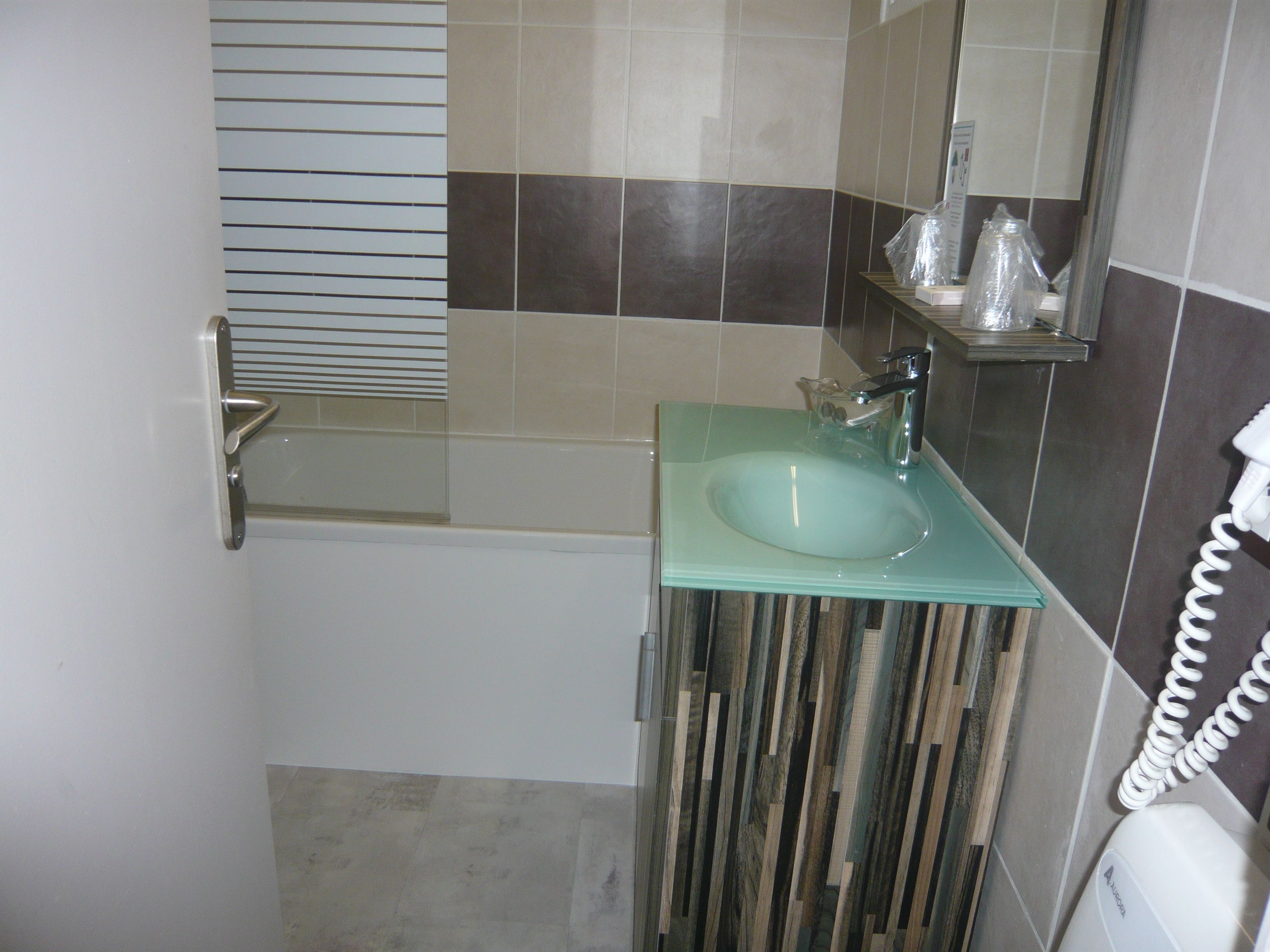 Un baño con un lavabo de vidrio, un espejo y un perchero para toallas.