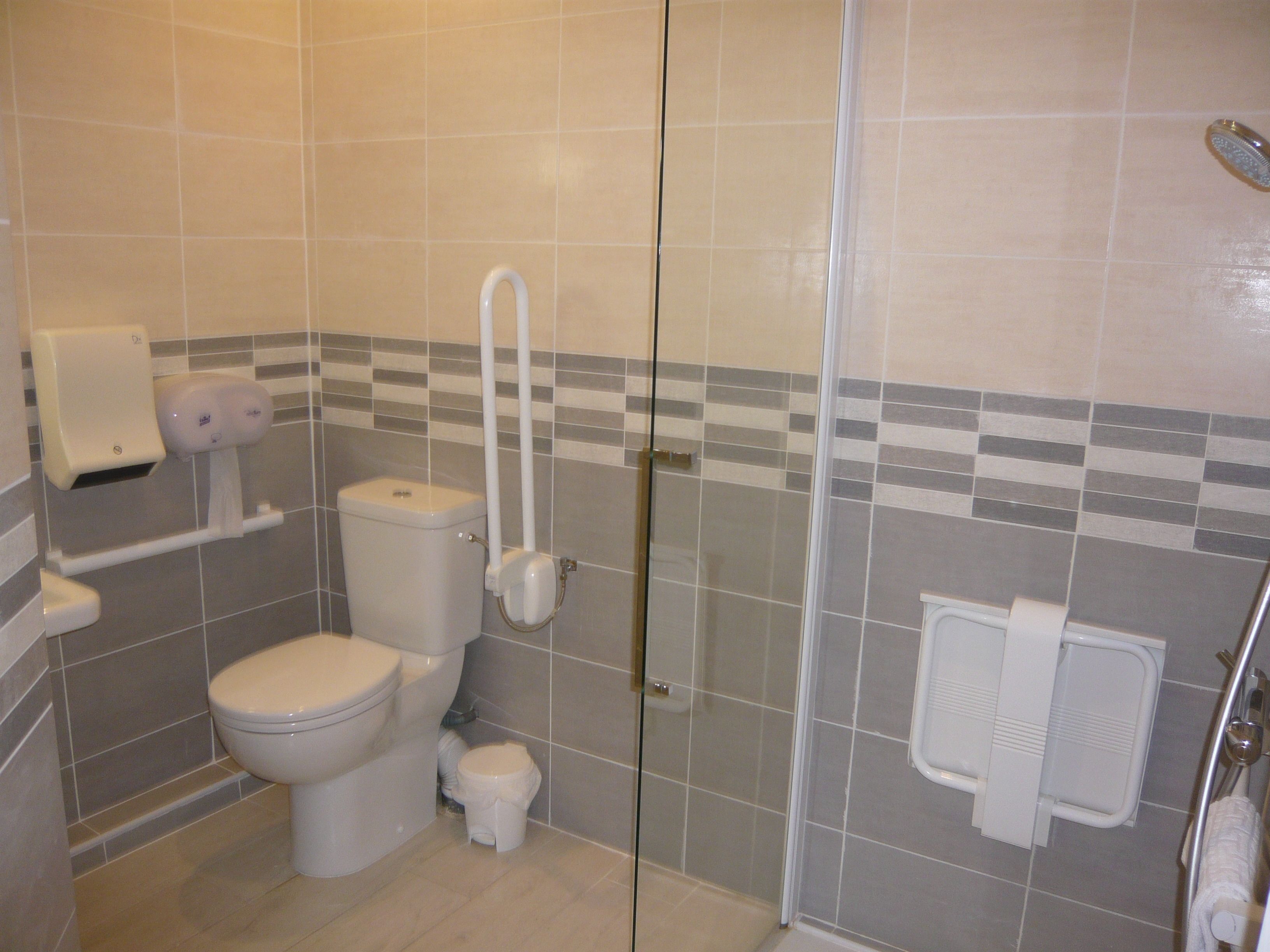 Et badeværelse med toilet, bidet og en brusekabine i glas.