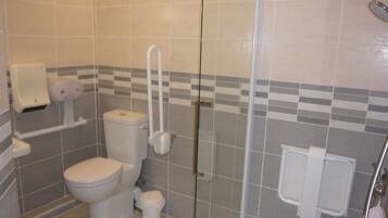 Et badeværelse med toilet, bidet og en brusekabine i glas.