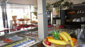 A buffet area with various food items and a fruit basket.