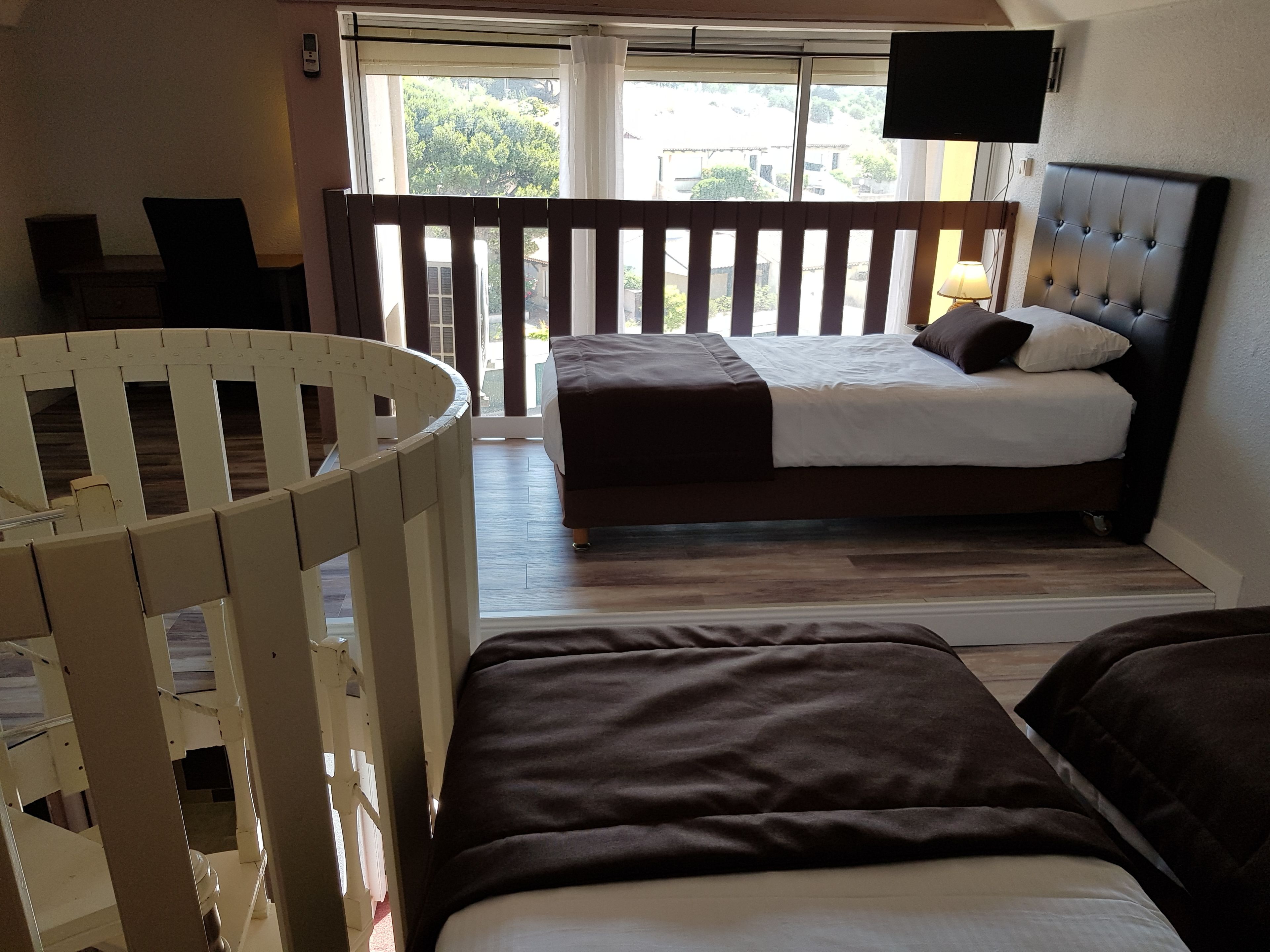 A bedroom with a bed, a crib, and a balcony with a railing.